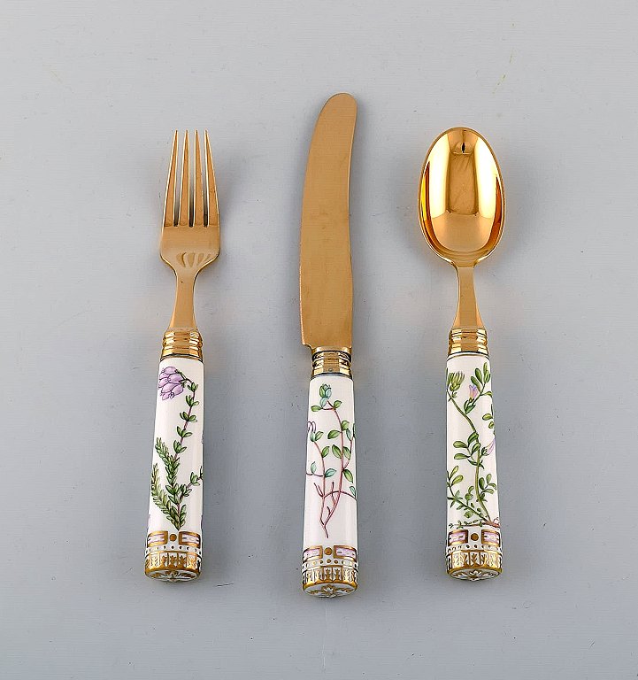 Michelsen for Royal Copenhagen. "Flora Danica" dinner set consisting of dinner 
knife, dinner fork and tableware in gold plated sterling silver. Porcelain 
handles decorated in colors and gold with flowers.
