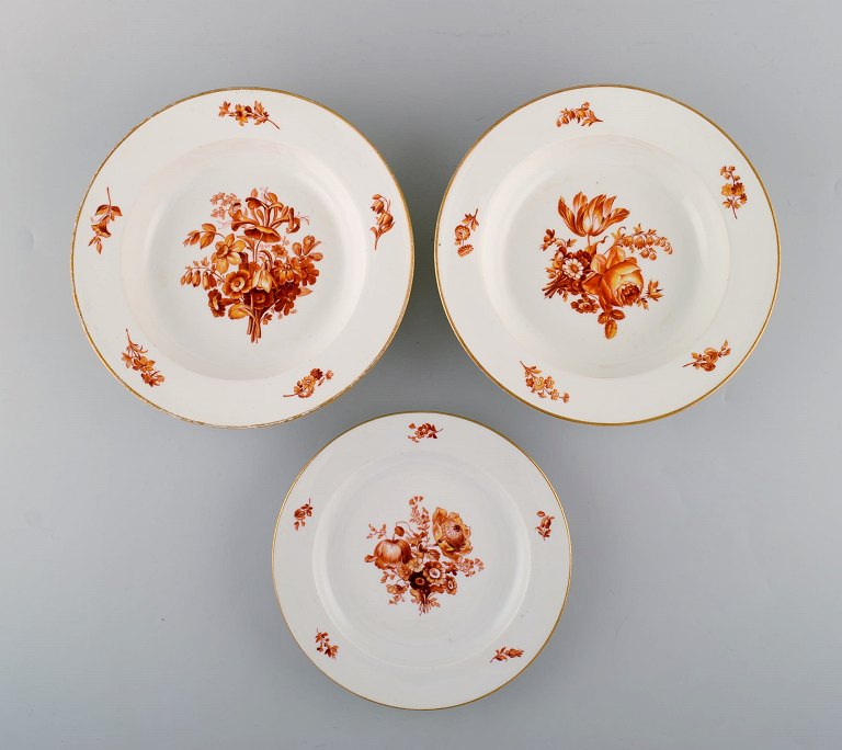 Tre antikke Meissen tallerkener i porcelæn med orange håndmalede blomster. To 
dybe tallerkener samt frokosttallerken. 1800-tallet.
