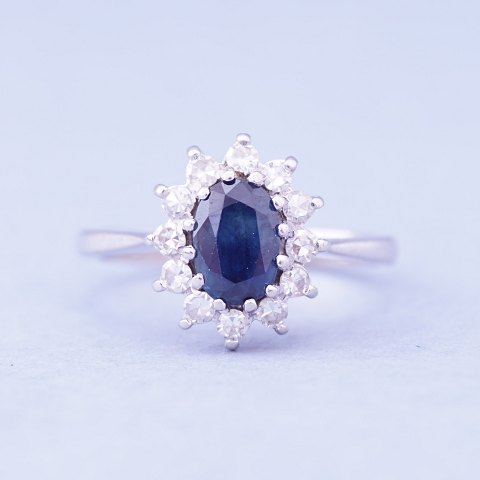 A ring set with a sapphire and wreathed with diamonds mounted in 14 kt. white 
gold