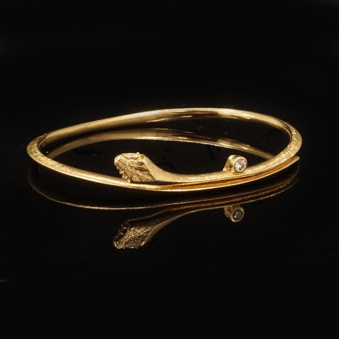 Ole Lynggaard Snakes armring. Oplukkelig oval 
armring i 18kt guld prydet med i alt 5 brillanter 
på i alt ca. 0,06ct. Stemplet Ole Lynggaard. 
Indvendige mål: 5,9x4,8cm