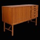 Peter Hvidt & Orla Mølgaard-Nielsen: Teak sideboard with five drawers and a 
rolling door.
A small scratch at the lower right front. Designed 1956. H: 87cm. L: 135cm. D: 
48cm