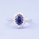 A ring set with a sapphire and wreathed with diamonds mounted in 14 kt. white 
gold