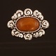 A large amber mounted silver brooch. Stamped by Thorvald Bindesbøll and Holger 
Kyster, Denmark. Size: 6,5x5cm