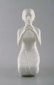 Harald Salomon for Rörstrand, white glazed figure of Balinese holding flower in 
her hand.