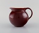 Royal Copenhagen / Aluminia Confetti jug in burgundy red glazed faience. 
Mid-20th century.
