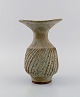 Lucie Rie (f. 1902, d. 1995, østrigsk-født britisk keramiker. Stor modernistisk 
unika vase i glaseret keramik / stentøj. Smuk glasur i lyse jordnuancer. Rillet 
korpus. Trumpet formet munding. Eget værksted, ca. 1970.
