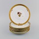 Syv Royal Copenhagen Guldkurv frokosttallerkener i porcelæn med blomster og 
gulddekoration. Modelnummer 595/10521.
