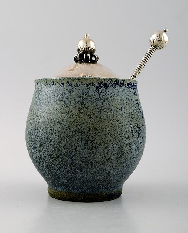 Arne Bang and others .: b. Frederiksberg 1901, d. Fensmark 1983.
Jam Jar in stoneware decorated with speckled blue-green glaze. 
Lid and spoon in sterling silver.