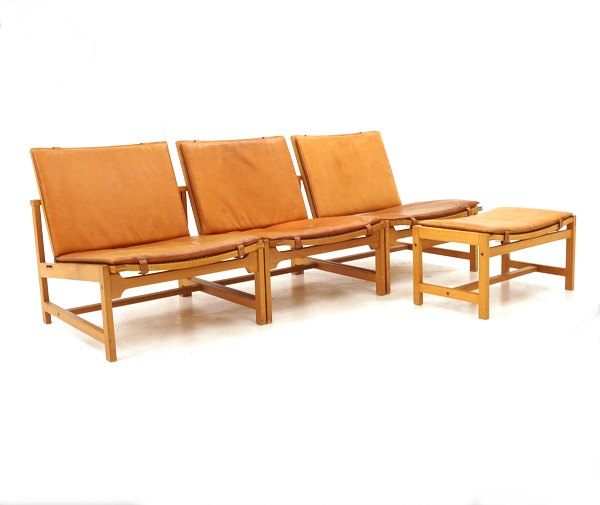 Arne Karlsen & Peter Hjorth: Satz von drei Lounge-Stühlen mit Schemel. Eiche mit 
patiniertem Leder. Ausgestellt in Milano 1961. L: 180cm. T: 70cm. Hs: 30cm. H: 
66cm