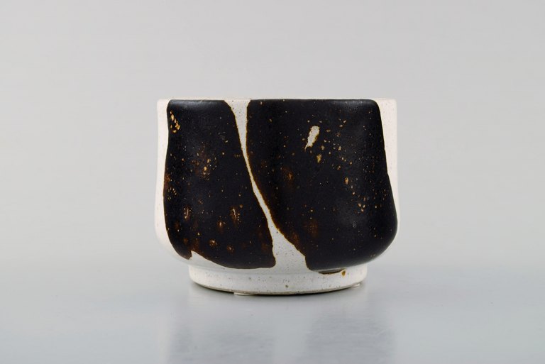 Lise Honoré, Danish ceramist. Small bowl in ceramic with glaze in brown nuances 
on light background. Late 20th century.