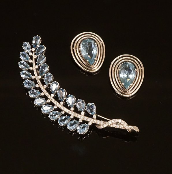 A 14kt whitegold set of brooch with diamonds and two earclips. Brooch L: 9cm. 
Earclips: 2x2,5cm