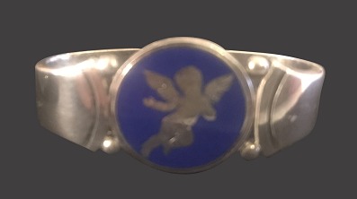 Servietring med engel og blå emaljeGeorg Jensen 1945-52Sterling sølv2,3 cm x 4,7 cm, 26 gGod standHarald Nielsen