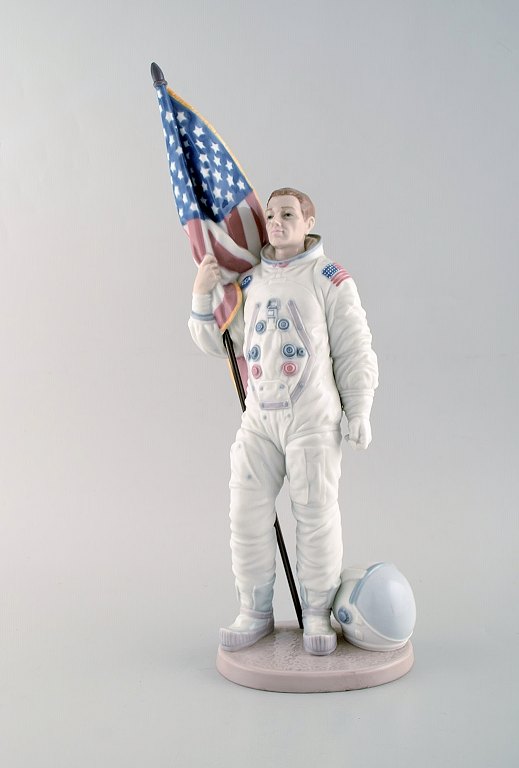 Lladro, Spain. Large rare figure in glazed porcelain. American astronaut in 
space suit holding stars and stripes. "The apollo landing". 25th anniversary. 
Dated 1994-95. Limited edition.
