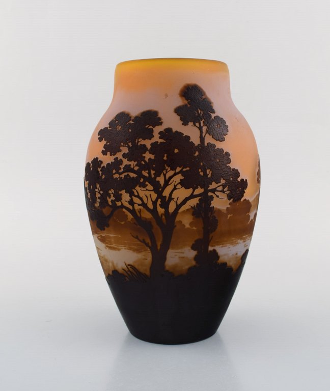 Tidlig Emile Gallé vase i ravfarvet kunstglas med brunt overfang udskåret med 
motiver af træer og solnedgang. Tidligt 1900-tallet.
