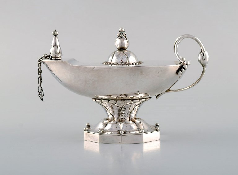 Early Georg Jensen oil lamp in sterling silver. Lid and stem with foliage. Edged 
base with pearls. Design 12. Dated 1933-44.
