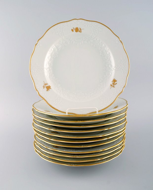 12 Meissen porcelain dinner plates with flowers and foliage in relief and gold 
decoration. 20th century.
