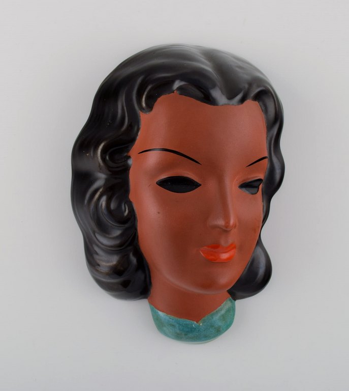 Goldscheider, Austria. Art deco female face in handpainted glazed ceramics. 
Dated 1953.
