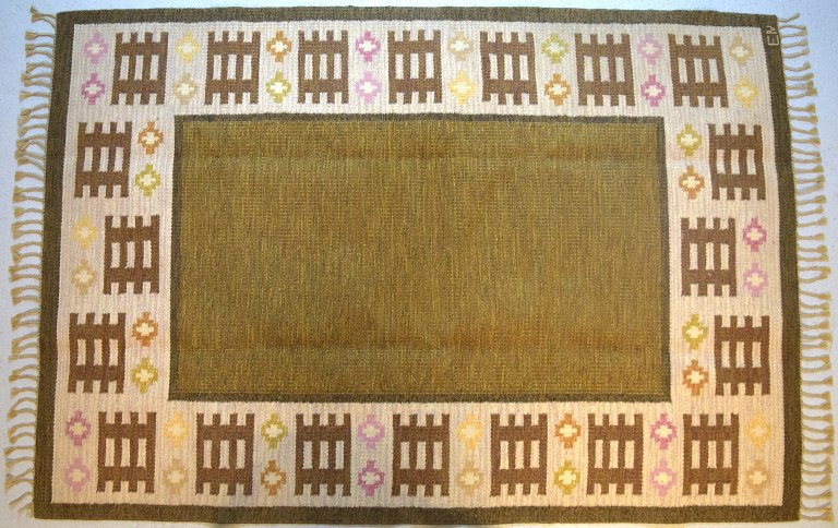 Swedish textile designer. Hand-woven RÖLAKAN rug with geometric fields in olive 
green, brown, yellow and pink shades. Mid-20th century.
