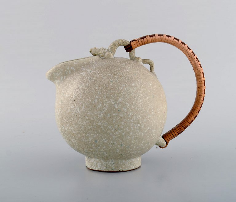 Arne Bang (1901-1983), Denmark. Jug in glazed ceramics with handle in wicker. 
Model number 151. Beautiful speckled glaze in sand shades. 1940s / 50s.
