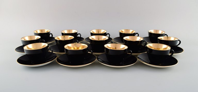 14 Royal Copenhagen / Aluminia Confetti coffee cups with saucers in black glazed 
faience with gold inside. Mid-20th century.
