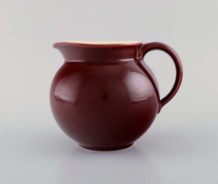 Royal Copenhagen / Aluminia Confetti jug in burgundy red glazed faience. 
Mid-20th century.
