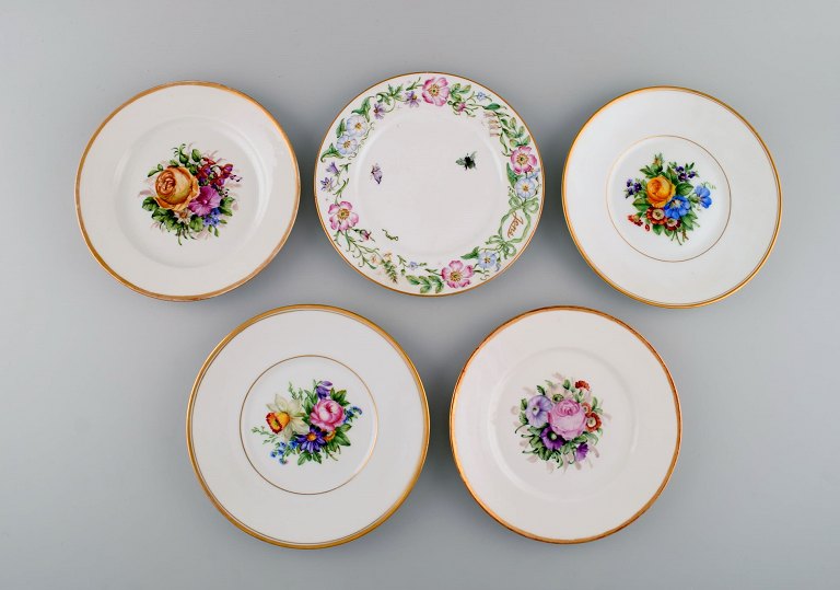 Fem antikke Royal Copenhagen tallerkener i porcelæn med håndmalede blomster, 
insekter og guldkant. Sent 1800-tallet.
