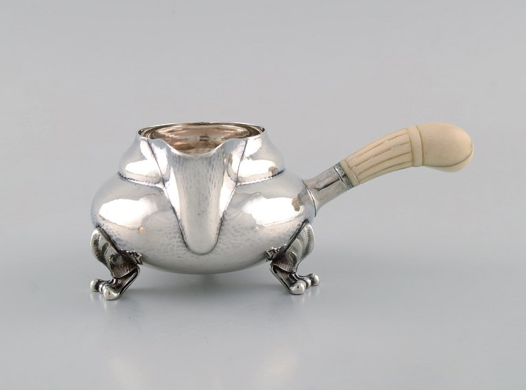 Georg Jensen Magnolia flødekande i hammerslået sterlingsølv med håndtag i 
elfenben. Model 2C. Dateret 1915-1930.
