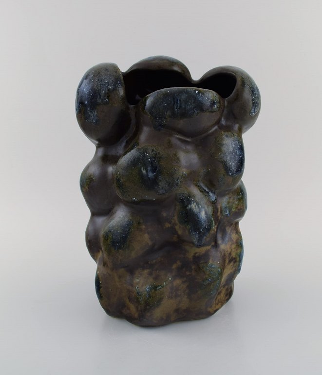 Christina Muff, dansk samtidskeramiker (f. 1971). Stor skulpturel unika vase i 
glaseret stentøj. Smuk brunsort mat glasur med blå toppe og hvide mineraler.
