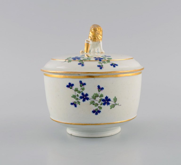 Antique German sugar bowl in hand-painted porcelain with flowers and gold edges. Lid knob modeled as a lion. 19th century.
