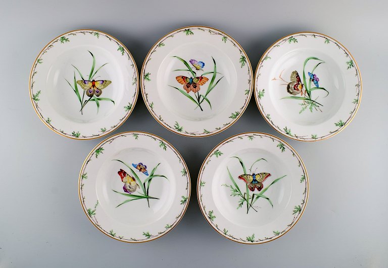 Fem antikke Royal Copenhagen dybe tallerkener i porcelæn med håndmalede 
blomster, sommerfugle og guldkant. Midt 1800-tallet.
