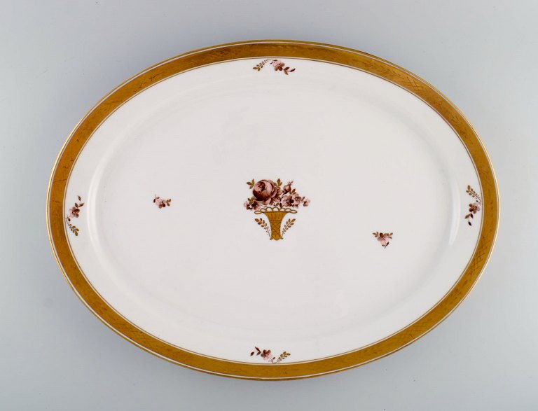 Stort ovalt Royal Copenhagen Guldkurv serveringsfad i porcelæn med blomster og 
gulddekoration. Modelnummer 595/9011. Tidligt 1900-tallet.
