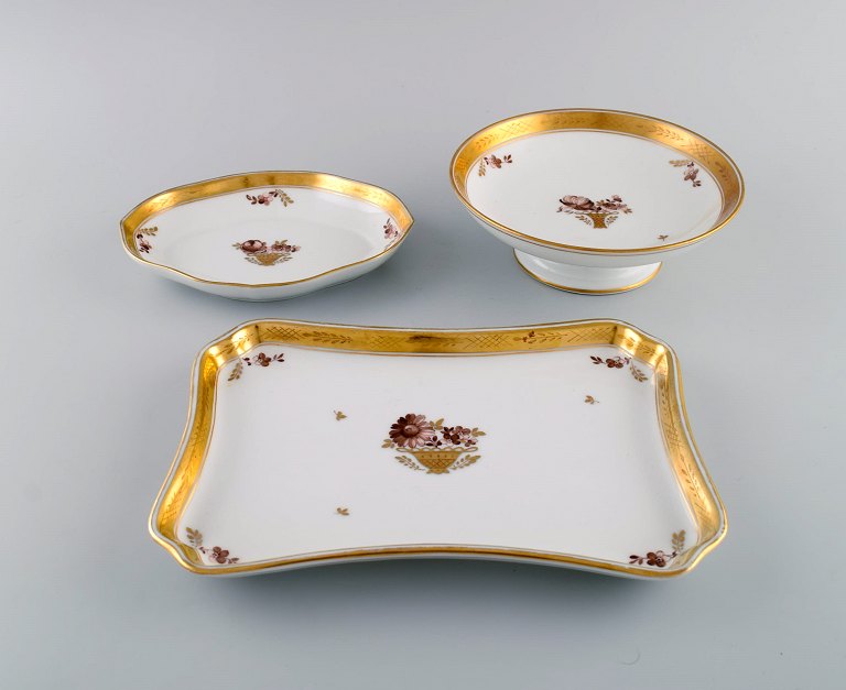 Tre Royal Copenhagen Guldkurv fade i porcelæn med blomster og gulddekoration. 
Tidligt 1900-tallet.

