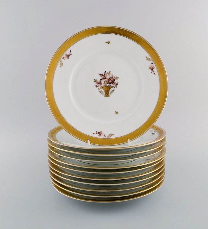 11 Royal Copenhagen Golden Basket porcelain dinner plates with flowers and gold 
decoration. Model number 595/10519. Early 20th century.
