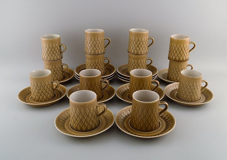 Jens H. Quistgaard (1919-2008) for Bing & Grøndahl / Nissen Kronjyden. 14 Relief 
kaffekopper med underkopper i glaseret stentøj. Smuk glasur i sennepsgule 
nuancer. 1960