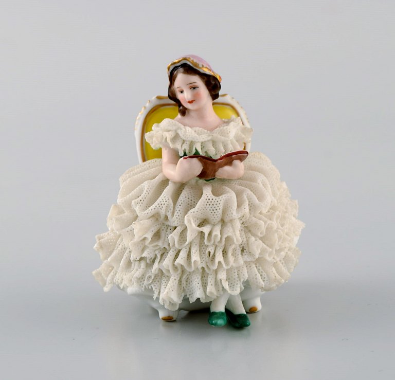 Volkstedt Rudolstadt, Germany. Porcelain figure. Reading woman in skirt. 
Mid-20th century.
