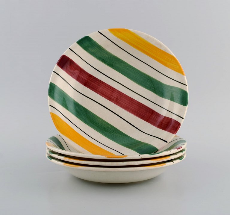 Longchamp, France. Four deep plates in glazed faience with hand-painted striped 
decoration. Mid-20th century.
