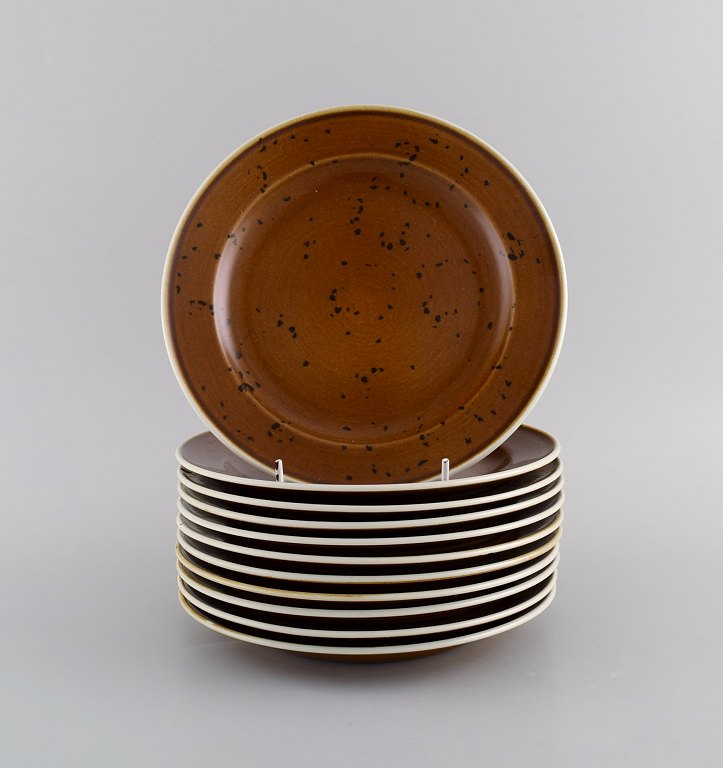 Stig Lindberg for Gustavsberg. 11 Coq frokosttallerkener i glaseret stentøj. 
Smuk glasur i brune nuancer. Svensk design, 1960