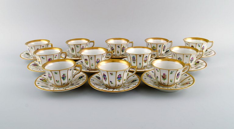 Tolv Royal Copenhagen Henriette kaffekopper med underkopper i håndmalet porcelæn 
med blomster og gulddekoration. Tidligt 1900-tallet. 
