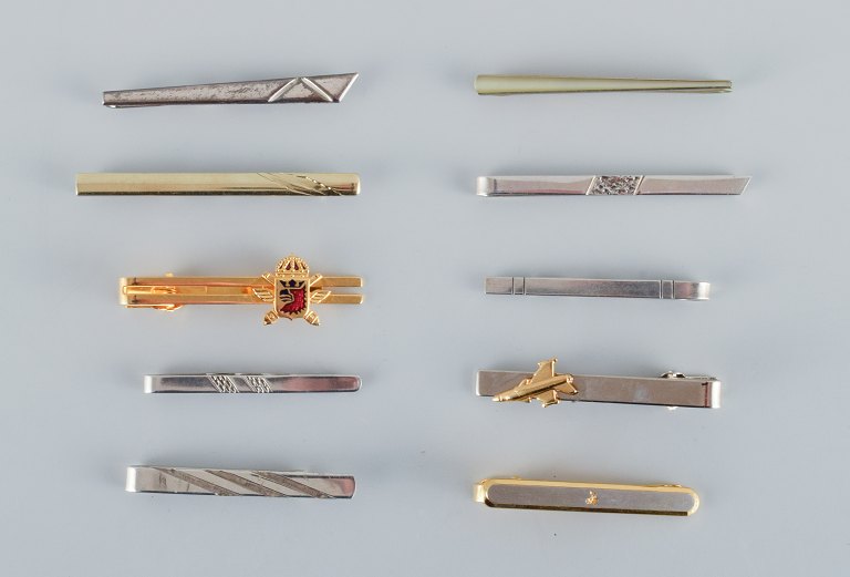En samling på ti danske slipsenåle i sterlingsølv og forgyldt metal.