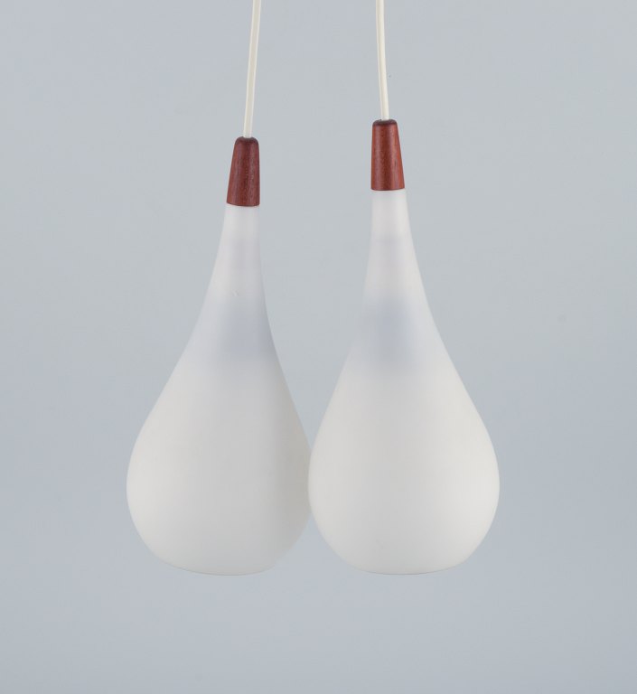 A pair of "Louis Poulsen" pendants in opal glass and teak.