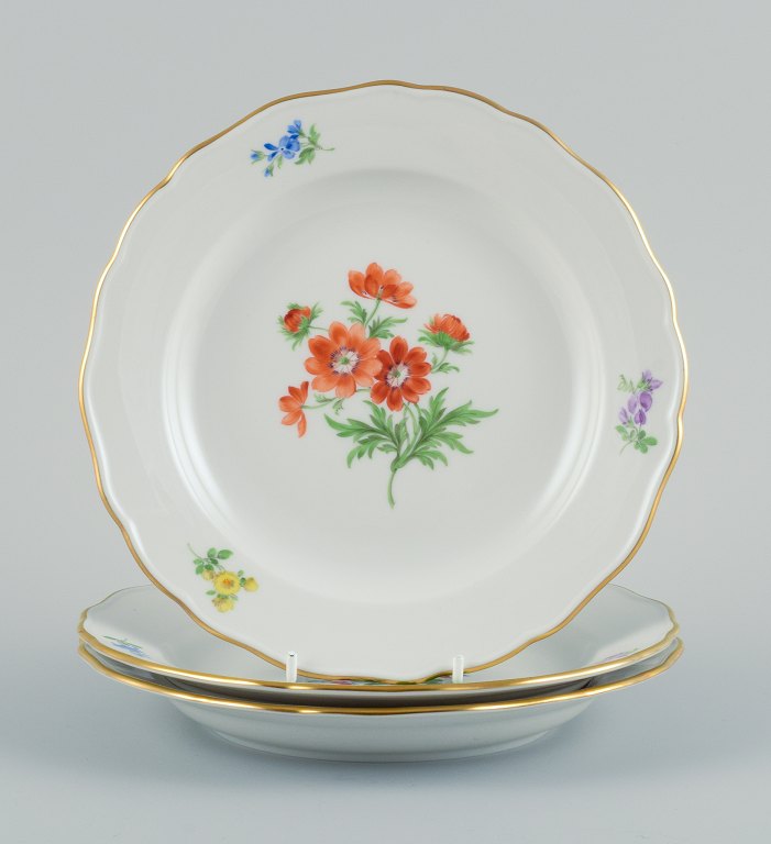 Meissen, Tyskland. Tre porcelænstallerkner håndmalet med forskellige 
blomstermotiver og guldkant.