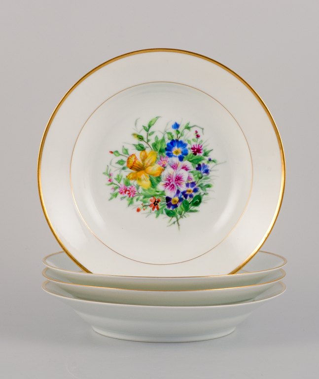 Bing & Grøndahl, four deep plates in porcelain hand-painted with polychrome 
flowers and gold decoration.