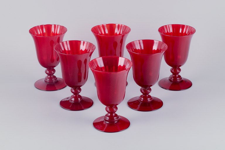 A set of six large wine glasses in red glass.