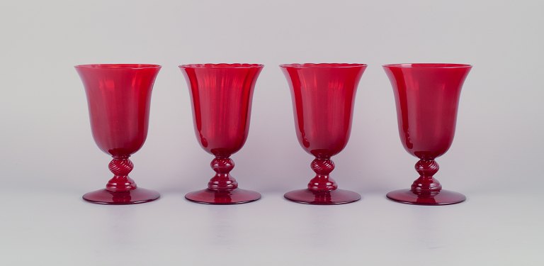 A set of four large red wine glasses.