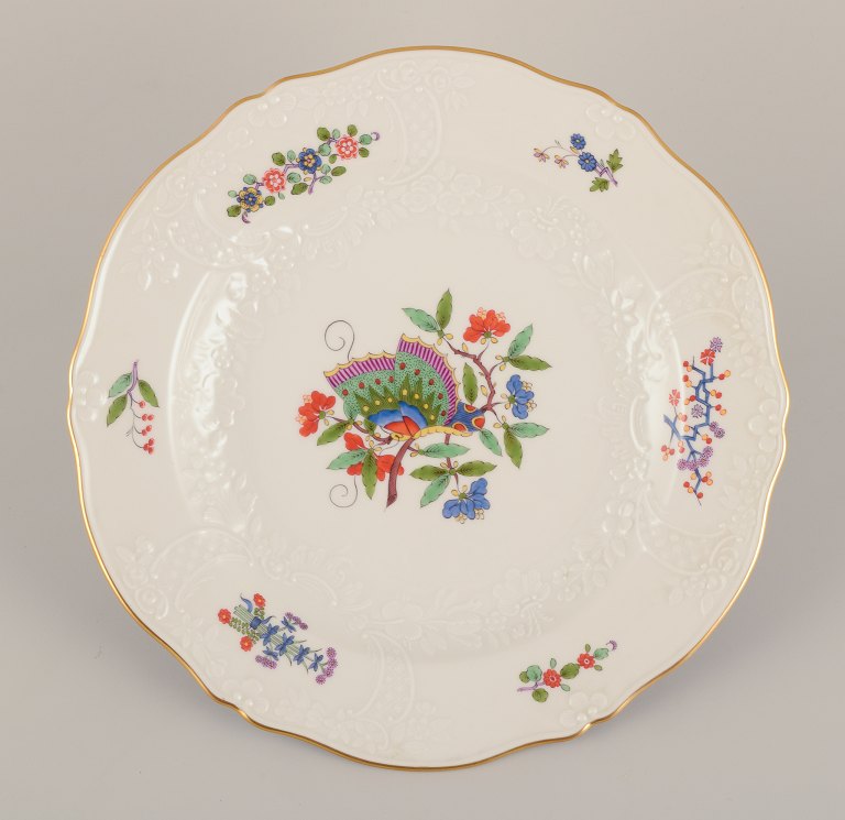 Meissen, Germany. Hand-painted dinner plate featuring a butterfly on a branch 
and polychrome flower motifs. Gold rim.