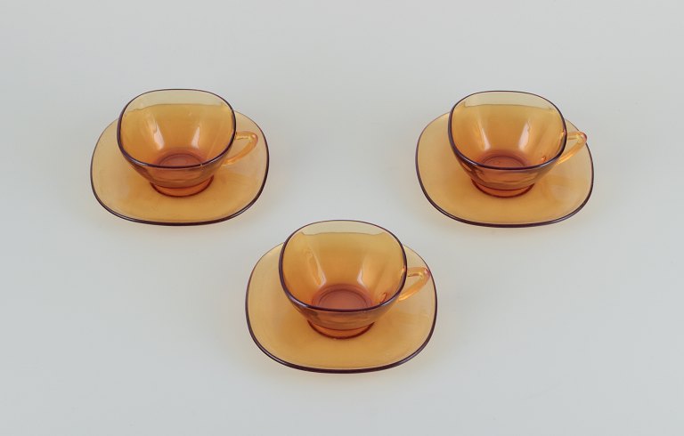 Vereco, Frankrig. Et sæt på tre kaffekopper med tilhørende underkopper i 
ravfarvet glas. Modernistisk design.