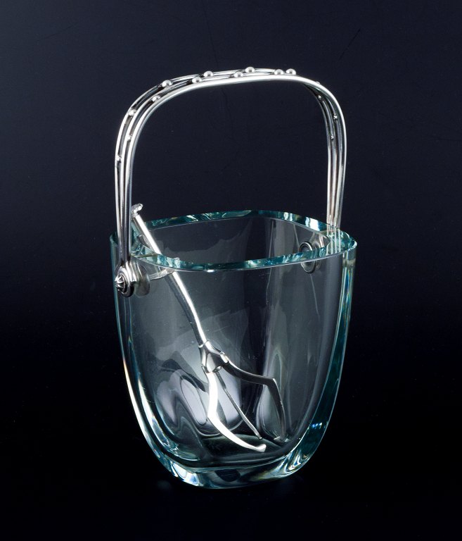 E. Dragsted, Danish silversmith.
Danish design. Modernist ice bucket in art glass with a sterling silver handle 
and a silver-plated metal ice tong.
Sleek Danish design.