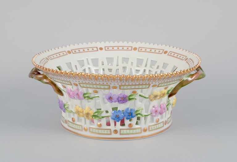 Royal Copenhagen Flora Danica frugtskål af porcelæn, dekoreret i farver og guld 
med blomster.