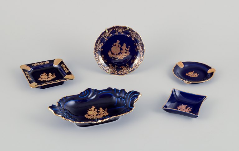 Limoges, Frankrig.  Fem dele porcelæn bestående af små fade og skåle. Dekoreret 
i 22-karat bladguld. Smuk kongeblå glasur. Scène galante.