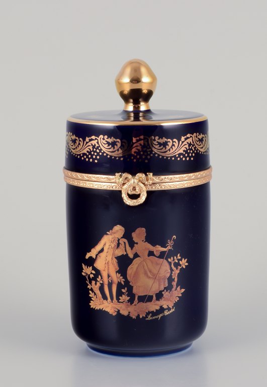 Limoges, France. Lidded porcelain box with brass mountings. Adorned with 
22-karat gold leaf and featuring a beautiful royal blue glaze with a Scène 
galante.